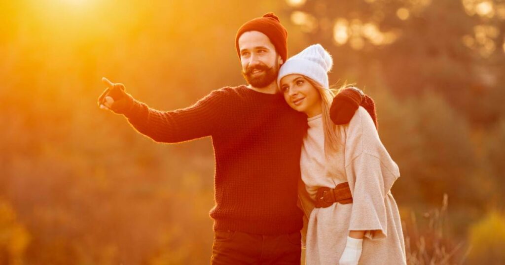 A joyful couple laughing together in a sunlit field, representing the successful manifestation of a happy relationship using the Law of Attraction.