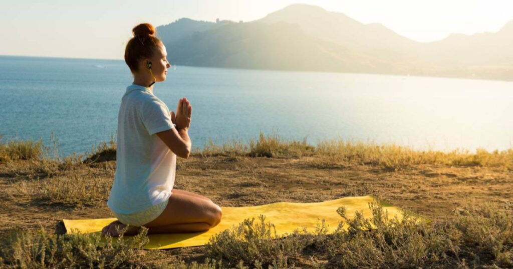 Woman practicing 10 minute morning meditation for manifestation at sunrise